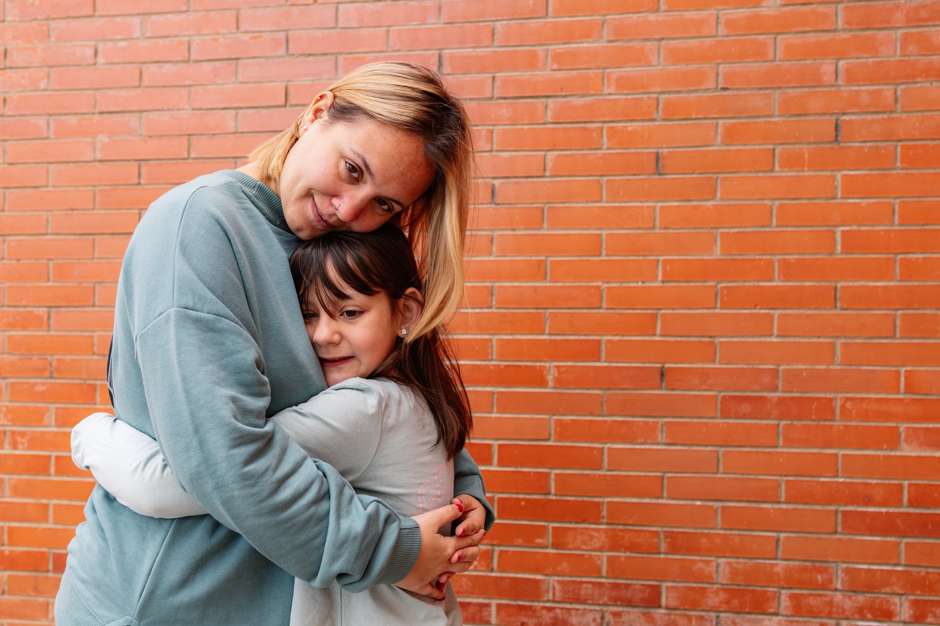 Happy Mother and Daughter against a Brick Wall